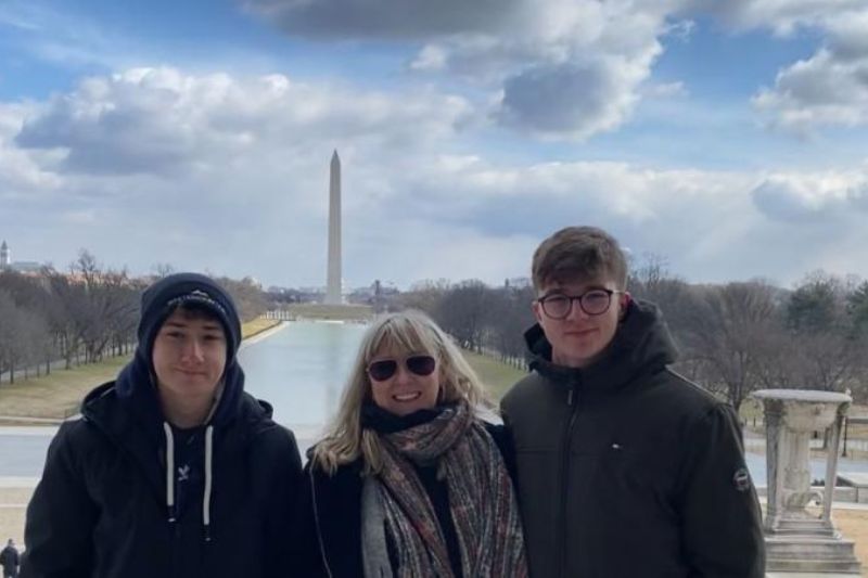 three student standing smiling to camera outdoors
